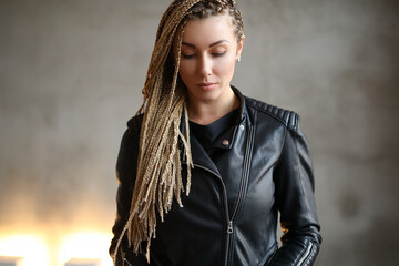 Photo of a beautiful, young, charmong woman with dreadlocks wearing leather jacket.