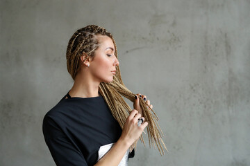 Close-up portrait of a young, beautiful woman with dreadlocks standing against stone background.