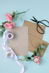 Cardboard envelope with scissors, ribbons and artificial flowers on a blue background