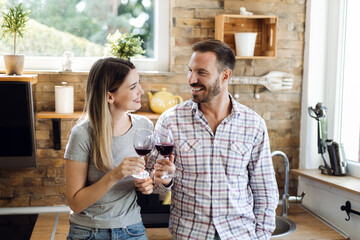 Happy young couple enjoying while drinking wine at home