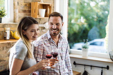 Happy young couple enjoying while drinking wine at home