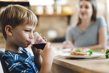 Profile view of small boy drinking fresh juice at dining table
