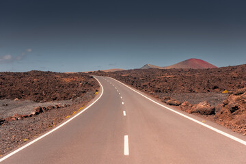 Empty road in the volcanic landscape of Timanfaya National Park, Lanzarote, Canary Islands,  Spain