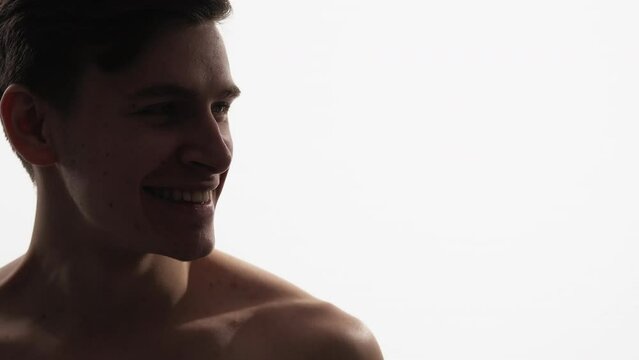 Smiling man portrait. Facial care. Grooming hygiene. Profile of satisfied shirtless handsome guy with clean face skin isolated on white empty space background.