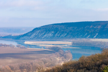 Beautiful view of the hilly valley with the river soothing winter nature. Background with copy space