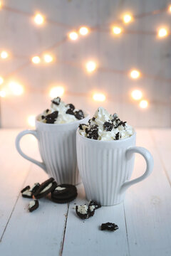 Side view of chocolate frappe coffee with whipped cream and oreo biscuits on wooden background