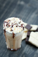 Top view of glass cup of Latte with whipped cream on top on a wooden surface.