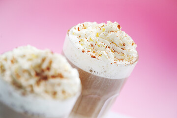 Close view of a tasty caramel milkshake on a pink background.