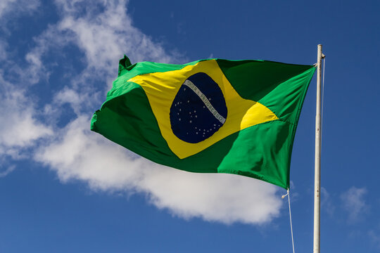 Foto de Bandeira do Brasil balançando ao vento com céu e nuvens ao fundo.  do Stock | Adobe Stock