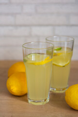 Two mason jar glasses of homemade lemonade on in bright kitchen. Fresh homemade tasty lemonade cold refreshing drink or beverage with ice