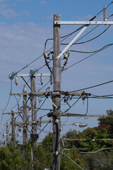 Electricity rural wooden utility pole with cables and insulators against blue sky