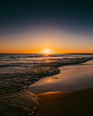 Shore of a beach in C&aacute;diz (Spain) in a summer sunset with reflections of the sun's rays on the wet sand.