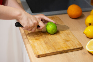 Close-up male hands cut green lime for a cocktail. Cooking delicious lemonade. Recipe and cooking tips. making cocktails. Slicing lemon fruit. Vegetarianism and veganism. Person cutting limes 