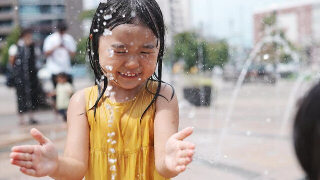 駅前広場の噴水で水浴びして遊んでいる女の子