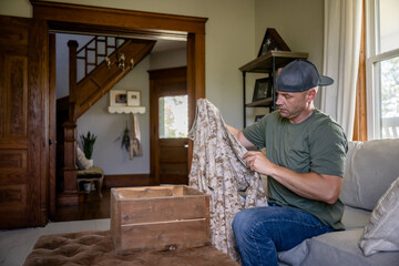 Marine veteran at home with family goes through uniforms and scrap book of military service.
