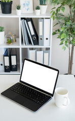 Computer mockup. Digital technology. Work place. Opened laptop with blank screen staying on desk with cup of coffee in light room interior.