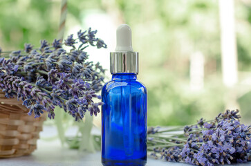 Blue bottle with lavender essential oil on nature background
