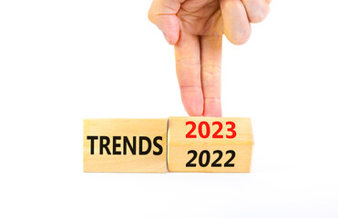 2023 trends new year symbol. Businessman turns a wooden cube and changes words Trends 2022 to Trends 2023. Beautiful white table white background, copy space. Business 2023 trends new year concept.