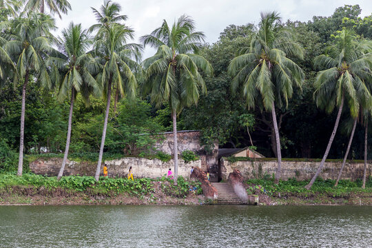 Bangladeshi people walking beside a bathing pond at the ancient Royal Palace of Natore 