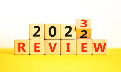 2023 review new year symbol. Turned a wooden cube and changes words Review 2022 to Review 2023. Beautiful yellow table white background, copy space. Business 2023 review new year concept.