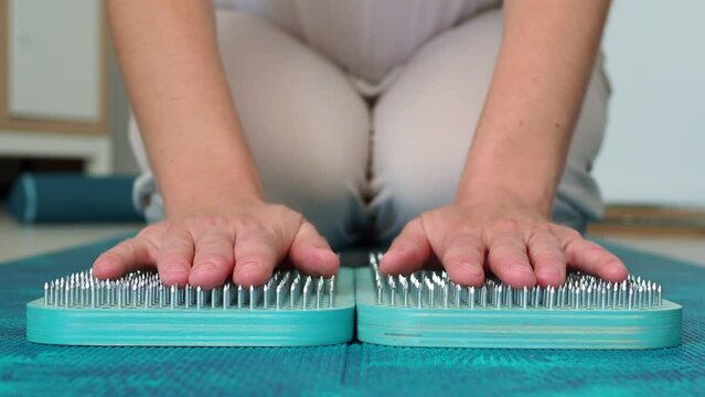 The woman puts her hands on the sadhu board. Side view. Turquoise wooden board for meditation and soul harmonization. Take the first step in the practice of sadhu yoga
