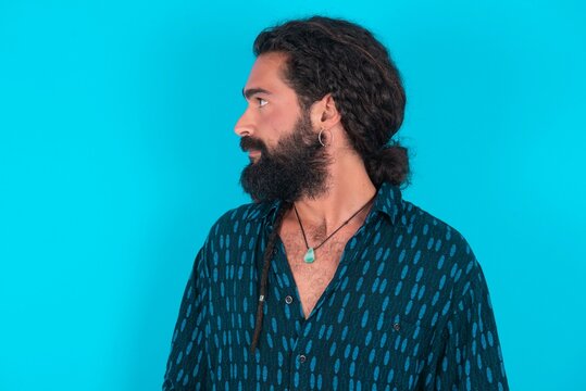 Side View Of Young Happy Smiling Young Bearded Man Wearing Blue Shirt Over Blue Studio Background