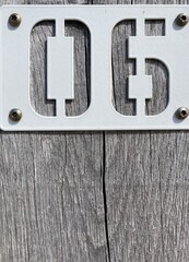 A white sign with the number 06 screwed on a gray wooden post