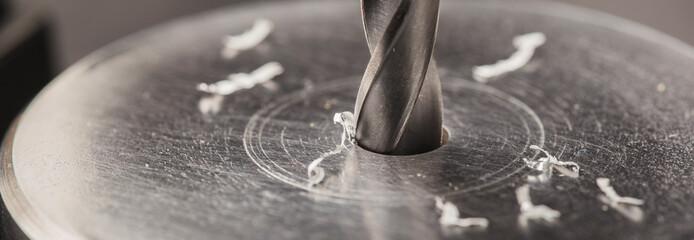 metal drill bit make holes in aluminum billet on industrial drilling machine with shavings. Metal...