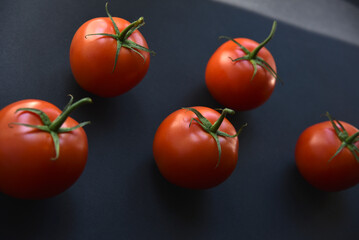 Several delicious red tomatoes in a row on a black background. Juicy red tomatoes close-up.