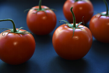 Several delicious red tomatoes in a row on a black background. Juicy red tomatoes close-up.