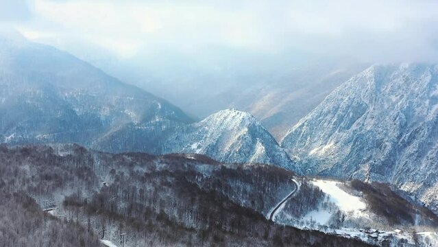 Hyperzoom of Mountain ridges with forest in foreground. Snowy tree branches in a drone view of winter forest. Trees covered with frost and snow. Aerial winter landscape at Bolu, Turkey Country
