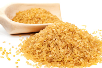 Bulgur wheat. Slide and scoop with grains of bulgur on a white background