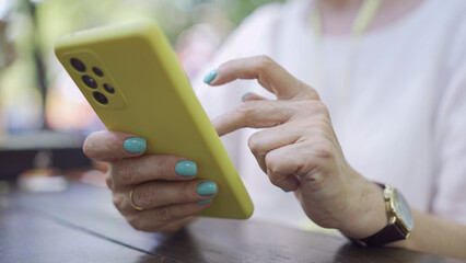 Close up of mature woman's hands use smartphone. Soft focus