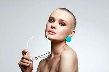 Obraz na płótnie Canvas beautiful girl with short haircut and fashionable glasses. stylish bald woman