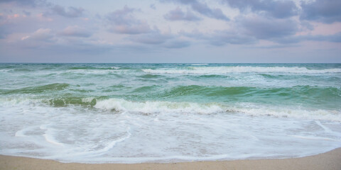landscape at the sea in the evening. green sea water. waves washing the shore. stormy weather forecast