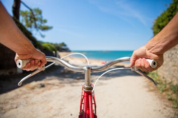 Obraz na płótnie Canvas Balade à vélo, cycliste tenant son guidon pour aller à la plage.