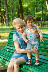 Fototapeta na wymiar beautiful girl with children sits on a bench in the park