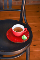 A red cup with tea is wrapped in a warm Christmas sweater, a tea bag label 