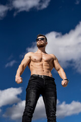 Athletic strong bodybuilder with naked torso. Shirtless muscular man outdoor posing.