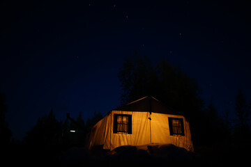 large expedition tent with protruding chimney from the furnace under the night starry sky