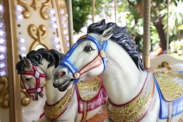 Fototapeta na wymiar A close-up of the carousel with horses. Carousel horse in a summer amusement park.