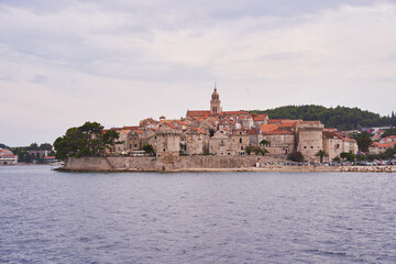 Fototapeta na wymiar Landscape picture of old town Korcula taken fom the adriatic sea during the cloudy summer day. Pitoresque historic old city on the Korcula island in south dalmatian region of Croatia.