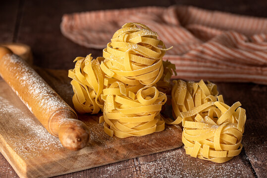 Food photography of raw pasta, tagliatelle, fettuccine, macro, rolling pin, board