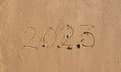 The numbers 2023 are written on the sand on the beach. The concept of the New Year. Happy New Year 2023 background. Travel during the Christmas holidays.