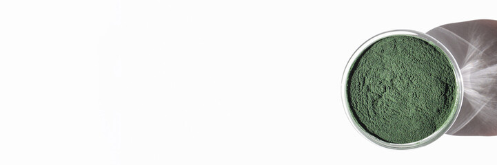 natural additives and superfood. green spirulina algae powder in glass on white background. healthy lifestyle concept. organic food banner copy space