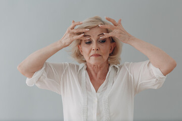 Elderly caucasian old aged woman gray haired portrait doing facebuilding yoga face gymnastics yoga...