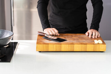 Close up of Chef cook hands chopping garlic. Professional chef cook cutting spice for Italian cuisine.
