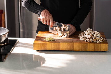 Close up of Chef cook hands chopping champignons. Professional chef cook cutting mushrooms for Italian cuisine