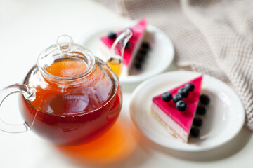 glass teapot with hot drink and cakes with berries. beverage for sweet dessert