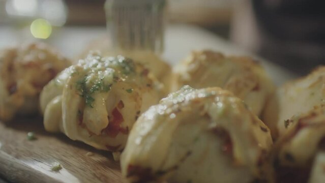 Close up shot of adding garlic butter to top of freshly baked bread buns with silicone brush